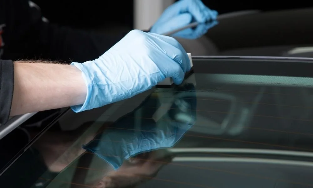 Person applying ceramic coating to a car window, showcasing detailing techniques for vehicle maintenance and protection.