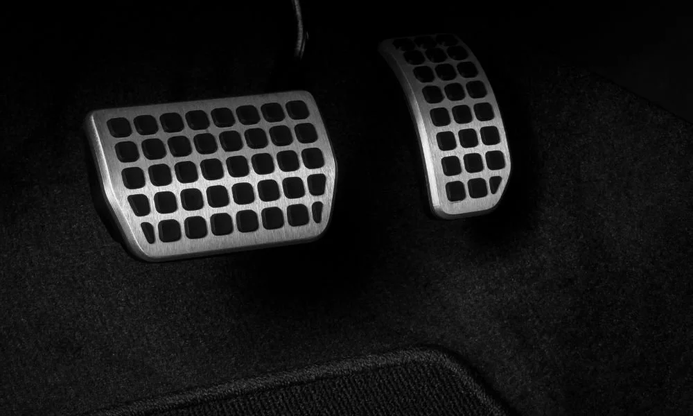 Car detailing image featuring metallic pedals on a dark carpet, highlighting often overlooked areas during vehicle cleaning.