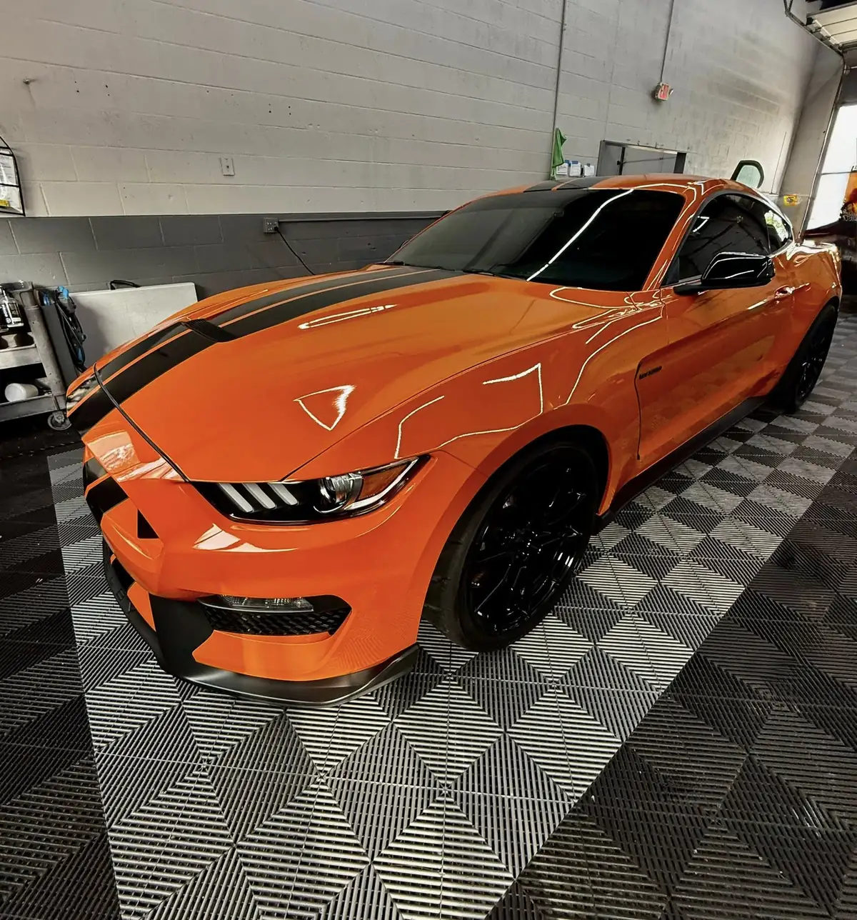 Orange sports car with black accents, showcasing a glossy finish and parked on a textured floor, highlighting Owner's Pride Ceramic Coating's vehicle protection services in Omaha, NE.